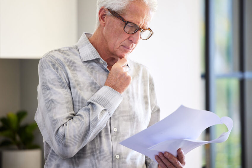 Idoso com papel na mão. Crédito: Freepik