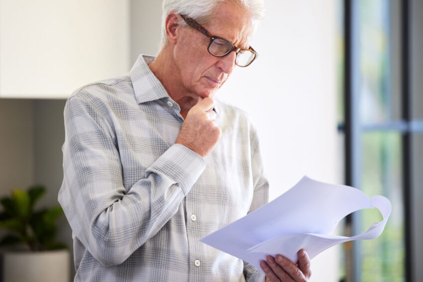 Idoso com papel na mão. Crédito: Freepik