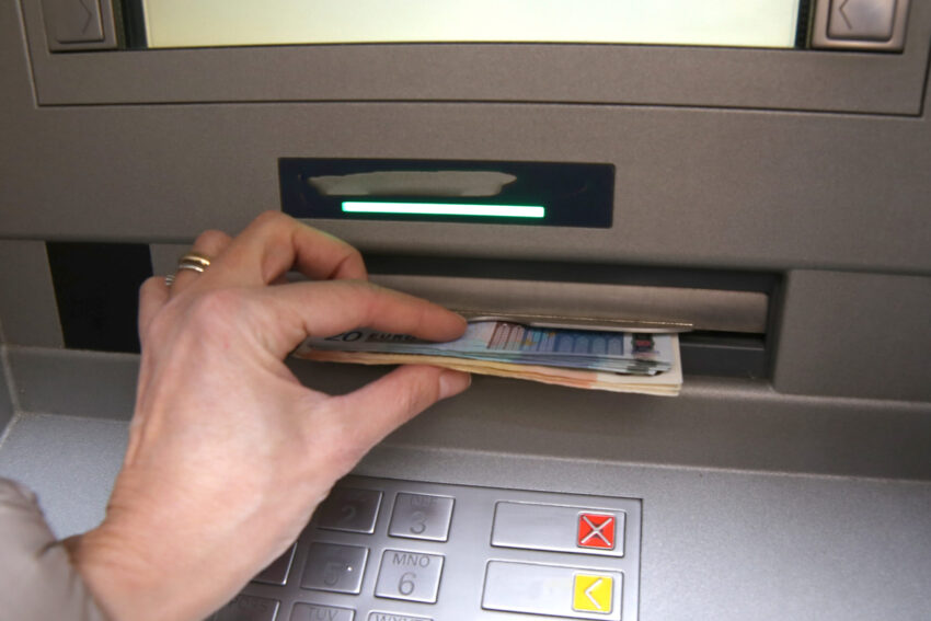 Mulher a retirar dinheiro de uma caixa Multibanco.