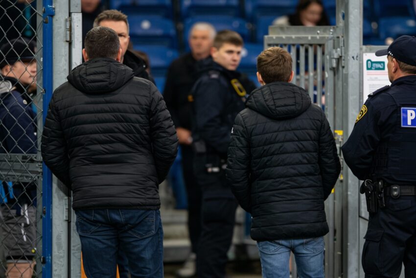 Pai e filho à porta de estádio de futebol.