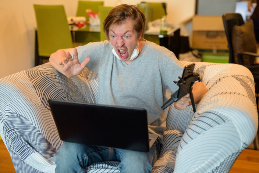 Homem sentado no sofá enraivecido em frente ao computador. Crédito: Freepik