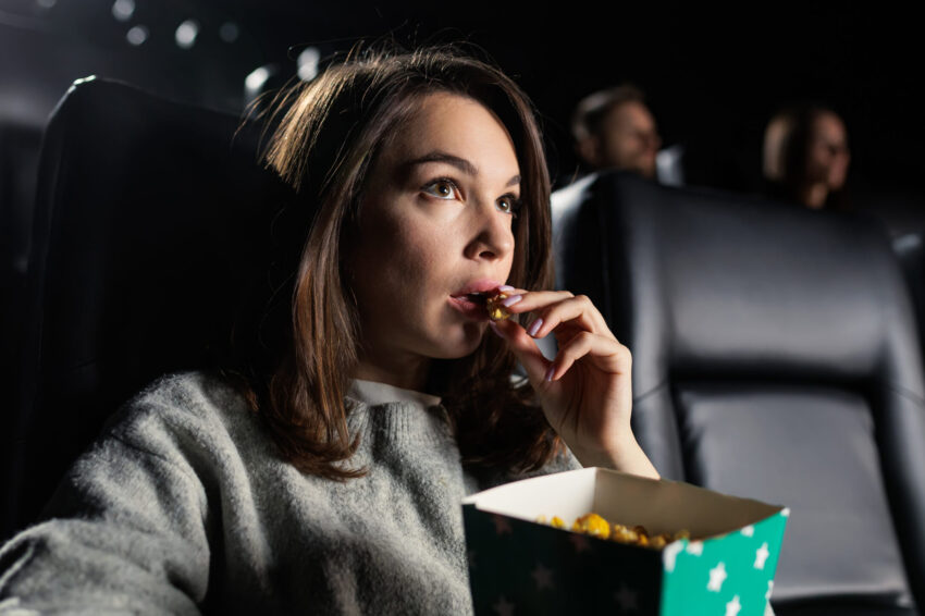Jovem a comer pipocas no cinema.