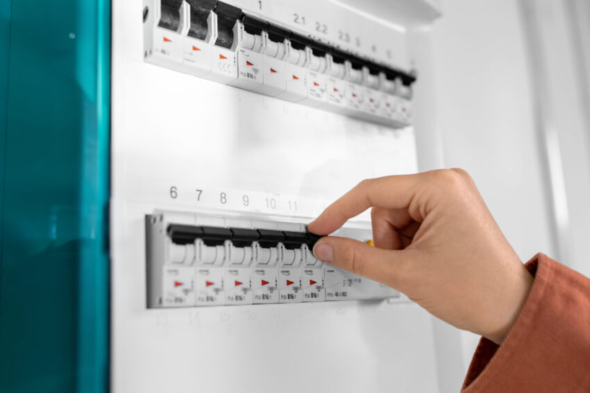 Pessoa a mexer nos disjuntores de um quadro elétrico. Crédito: Freepik