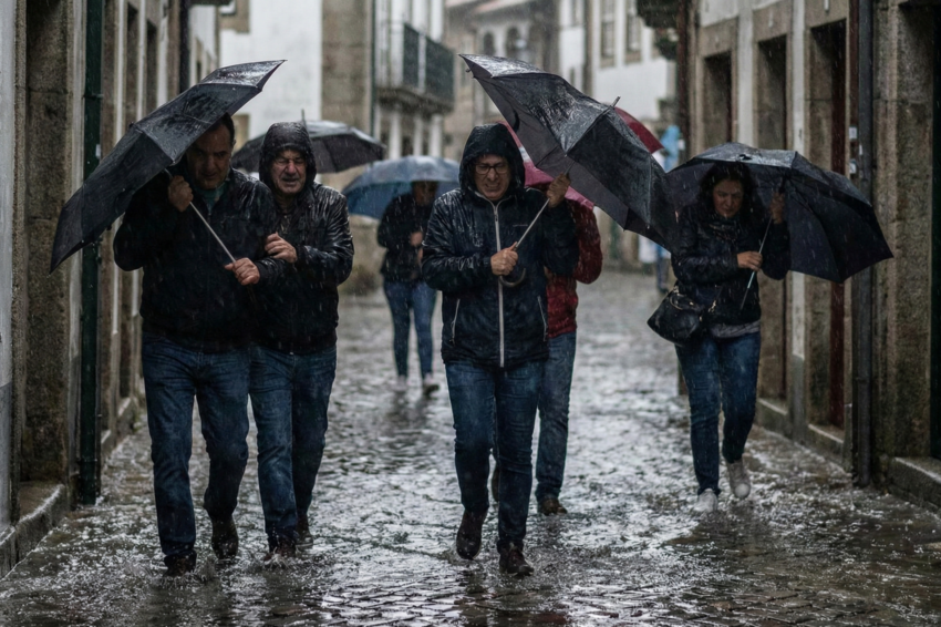 Várias pessoas debaixo de chuva forte. Crédito: Foto AI