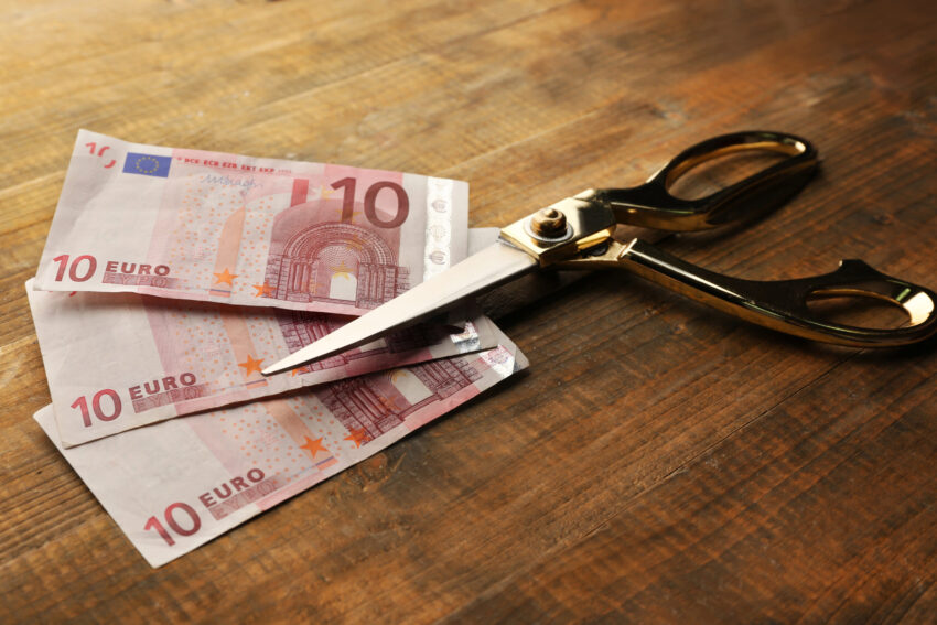 Três notas de 10€ e uma tesoura prestes a cortá-las. Crédito: Freepik