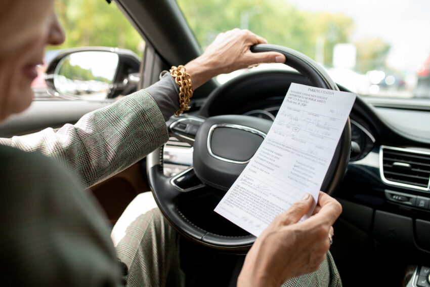 Mulher no carro a segurar um documento.