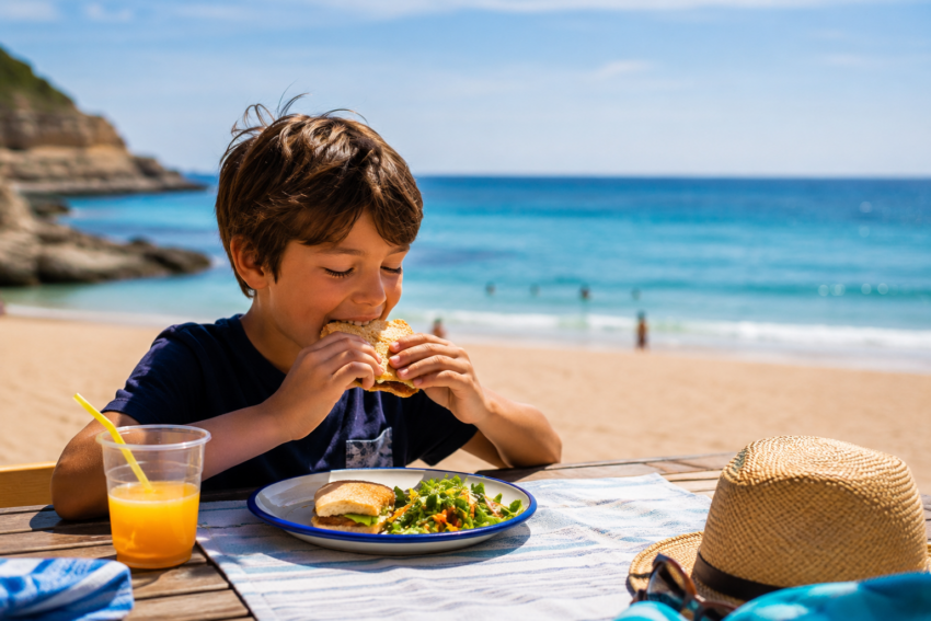 Criança a comer na praia. Crédito: Foto AI