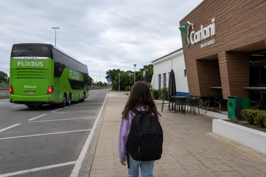 Menina observa autocarro FlixBus junto à área de serviço. Crédito: Foto AI