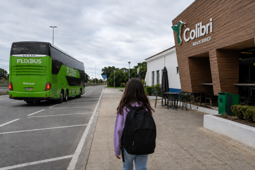 Menina observa autocarro FlixBus junto à área de serviço. Crédito: Foto AI