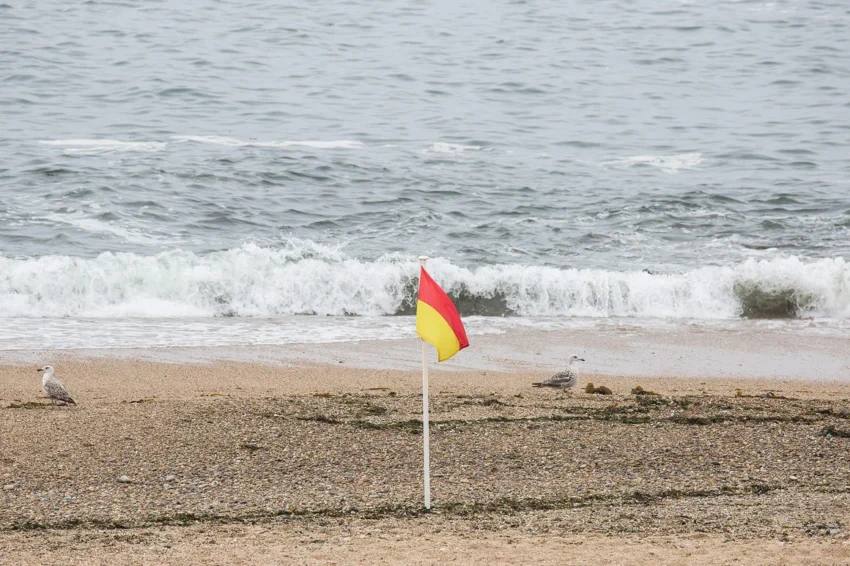 Bandeira com riscas amarela e vermelha na praia.
