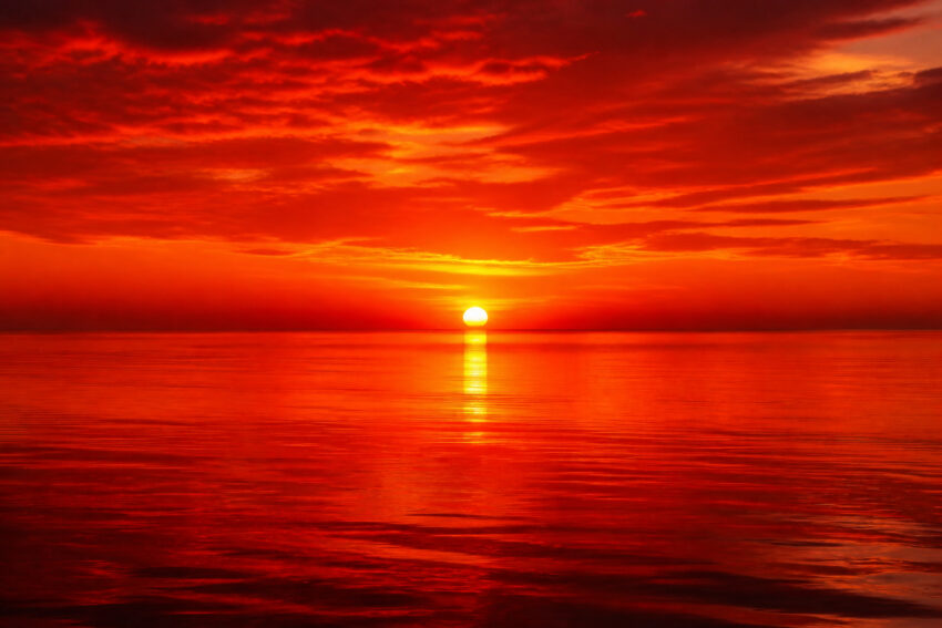 Céu avermelhado sobre o mar. Crédito: Magnific AI