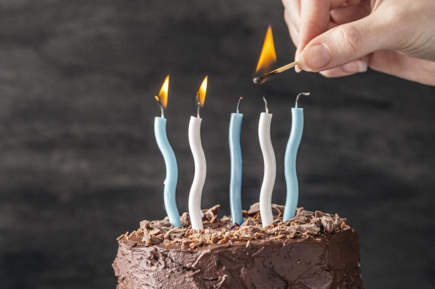 Homem a acender as velas de um bolo de aniversário.