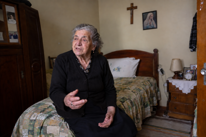 Idosa a dar entrevista. Crédito: POSTAL AI – imagem gerada por IA