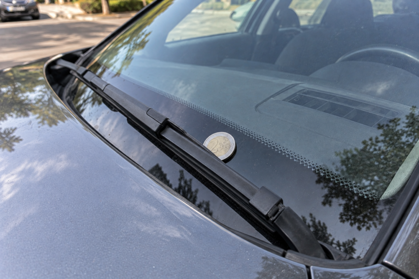 Moeda presa no para-brisas de um carro.