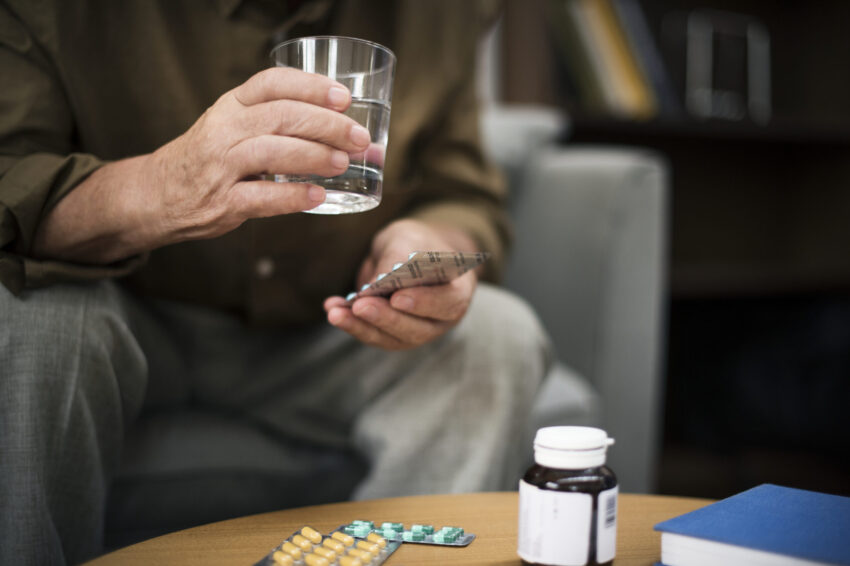 Homem a tomar medicamentos.